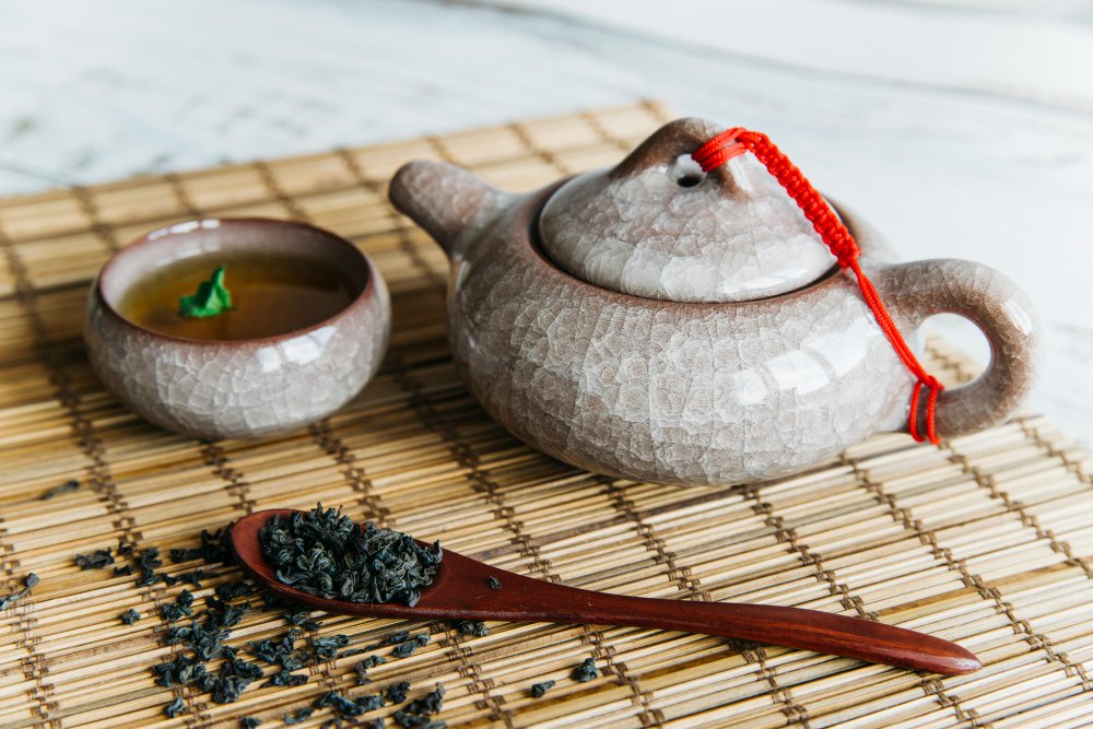 dried tea leaves with ceramic teapot teacups placemat